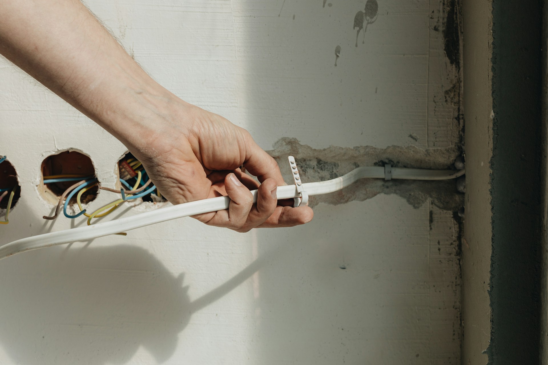 A person holding a white electrical wire