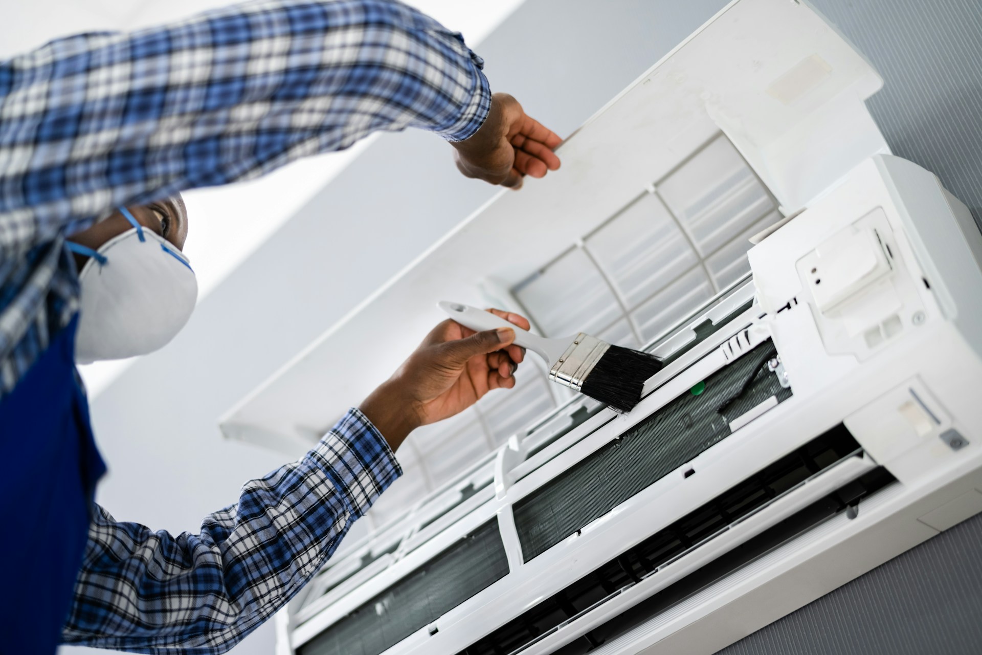 A person cleaning an air conditioner unit